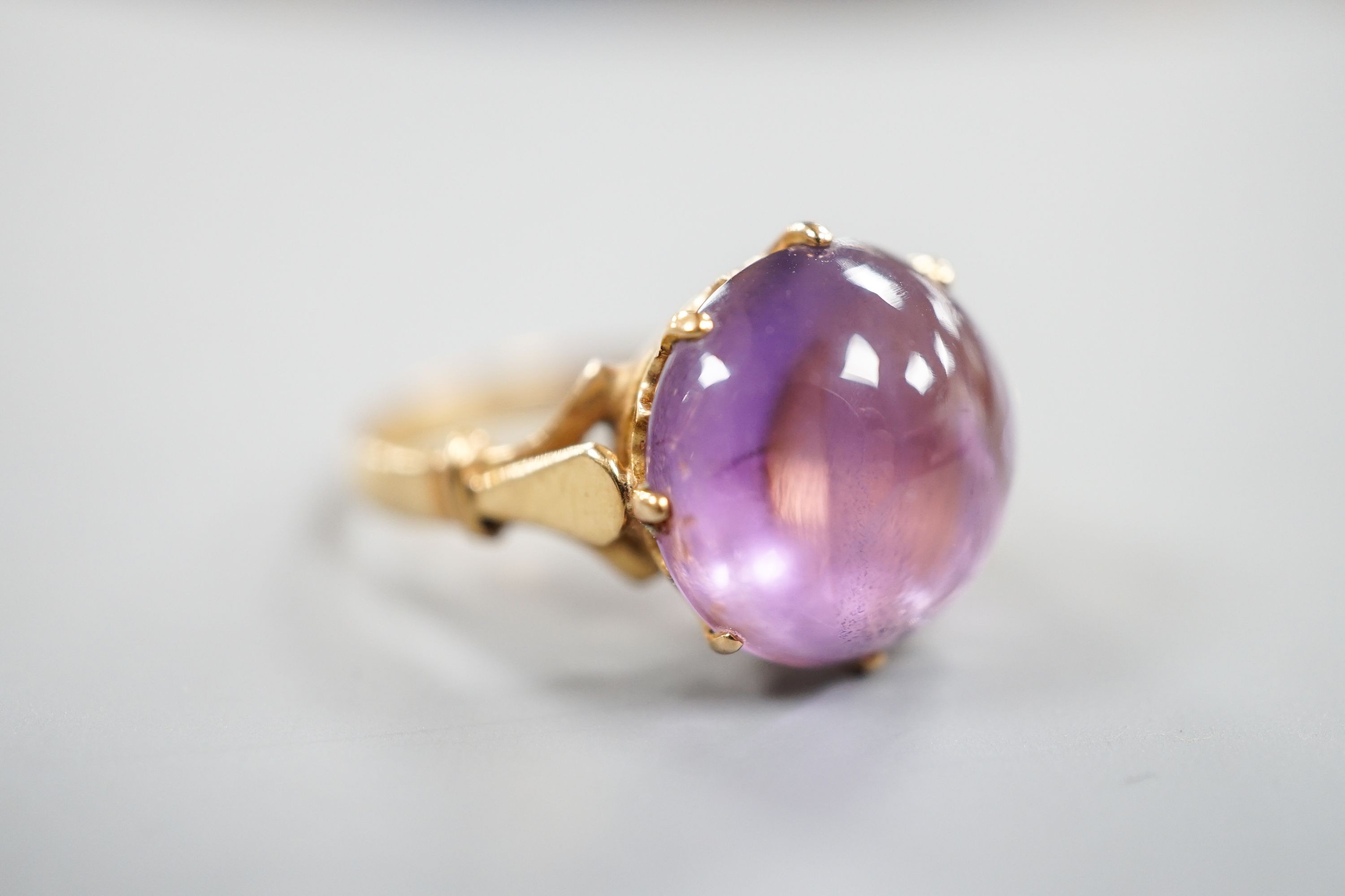An early 20th century yellow metal and button shaped cabochon amethyst set ring, size R/S, gross weight 5.5 grams.